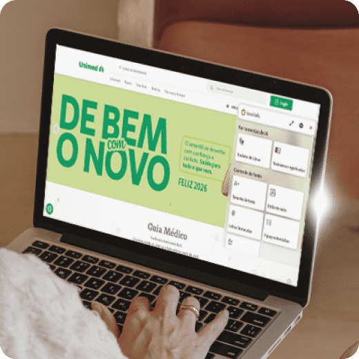 Fotografia de mesa com notebook em destaque. Na tela, o Plugin da Hand Talk funcionando no site da Unimed.