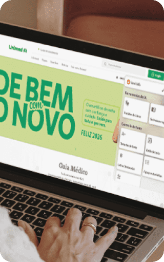 Fotografia de mesa com notebook em destaque. Na tela, o Plugin da Hand Talk funcionando no site da Unimed.
