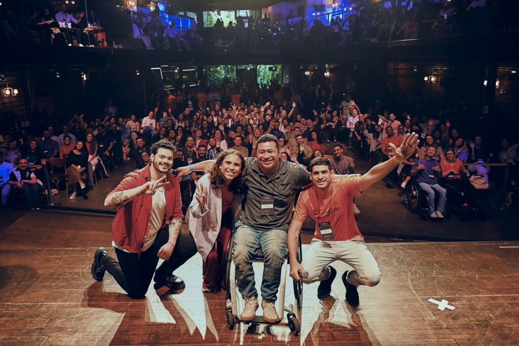 Foto demonstra pessoas sorrindo para a câmera, com público do Link atrás. Roberto Castejon, Eduardo Victor, Clodoaldo Silva e Ronaldo Tenório estão em destaque, abraçados e sorrindo.