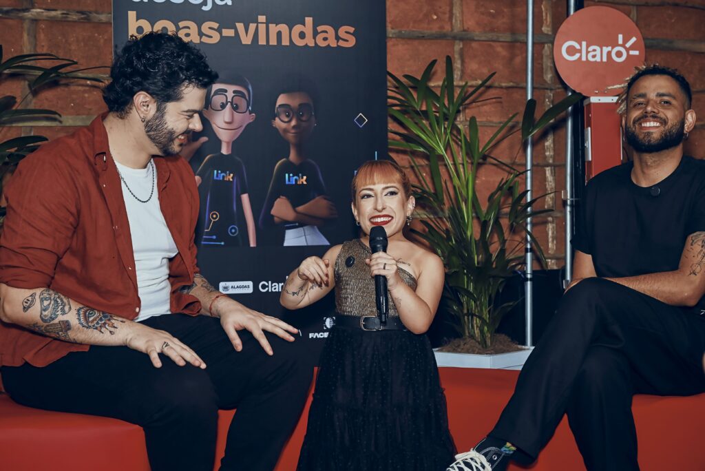 Foto demonstra Roberto Castejon, Stephanie Marques e Ricieri Palha. Roberto e Ricieri estão sentados, e Stephanie está em pé, no meio deles.