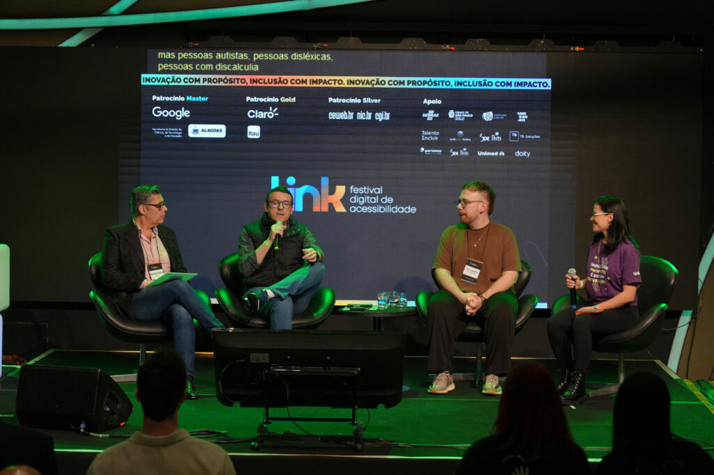 Representantes do Itaú, Avenues e Aprenda Brasil participam de um painel no palco, sentadas em poltronas. Atrás delas, o telão exibe a identidade do evento e os patrocinadores. Uma das pessoas fala ao microfone enquanto os demais escutam.